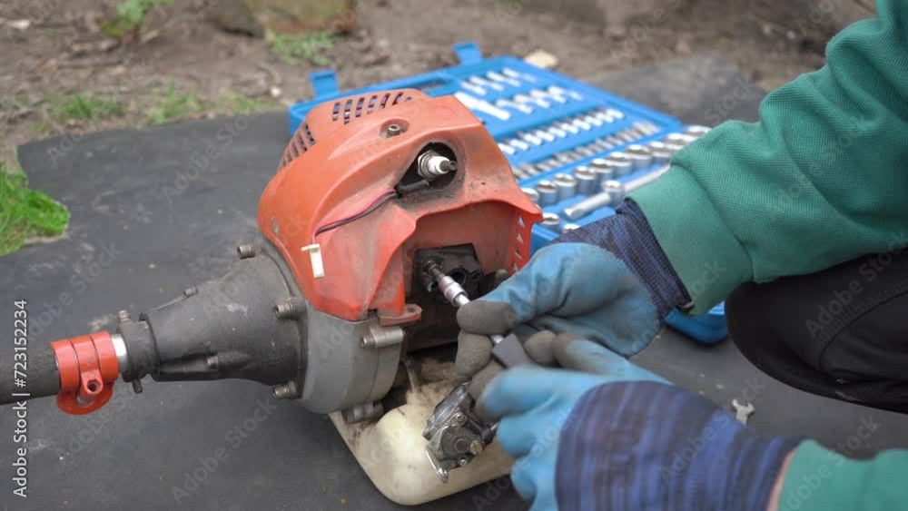 a man disassembles a mower,a man with a screwdriver disassembles a mower a man disassembles a mower,a man with a screwdriver disassembles a mower