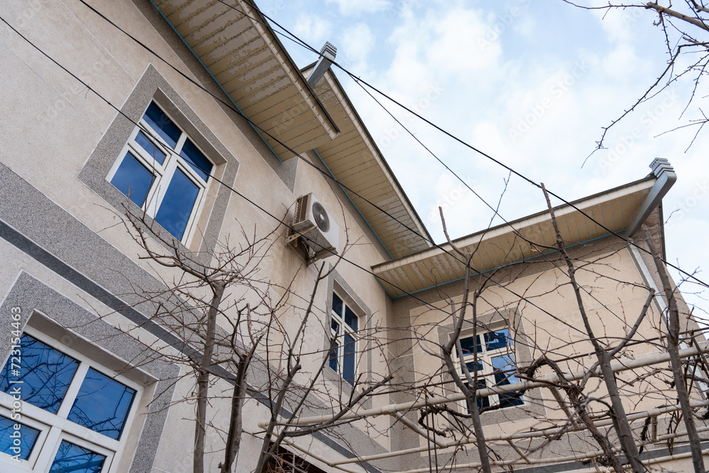 Obraz premium a two floor home with a ventilator and air conditioner outdoor unit with multiple blue windows and sky