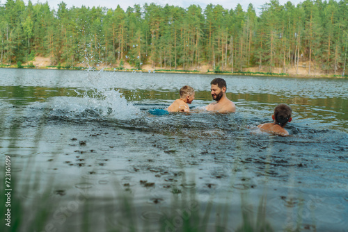 father and children swimming in forest lake. Man teaching son to swim