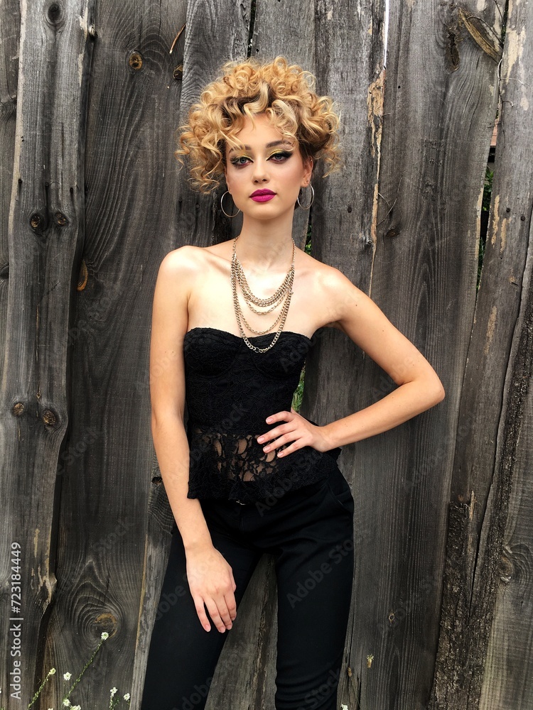 Fototapeta premium Sexy girl with a luxurious curly hairstyle and glamorous makeup in a lace top pose