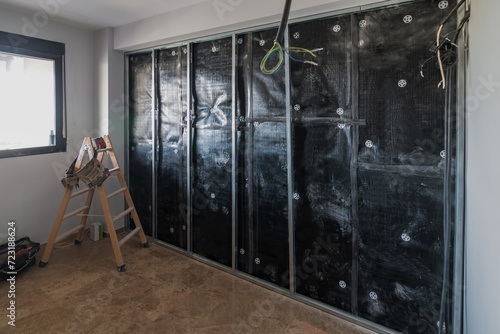 Bedroom in the process of insulating walls with acoustic insulation sheets and structure for plasterboard partition in work in progress. Home renovation concept