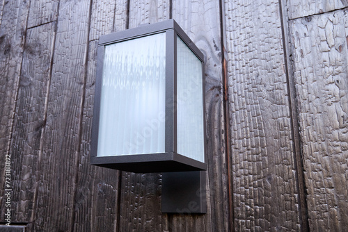 Modern external lamp on burned wood wall