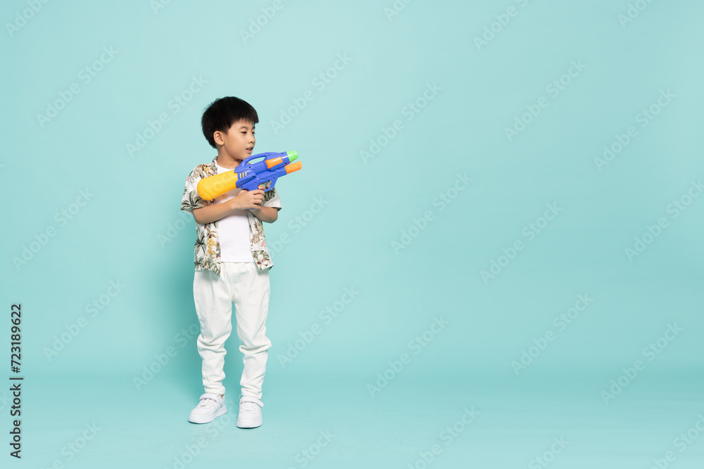 Asian little boy in summer outfits holding water guns plastic for Songkran festival in Thailand isolated on green background Asian little boy in summer outfits holding water guns plastic for Songkran festival in Thailand isolated on green background