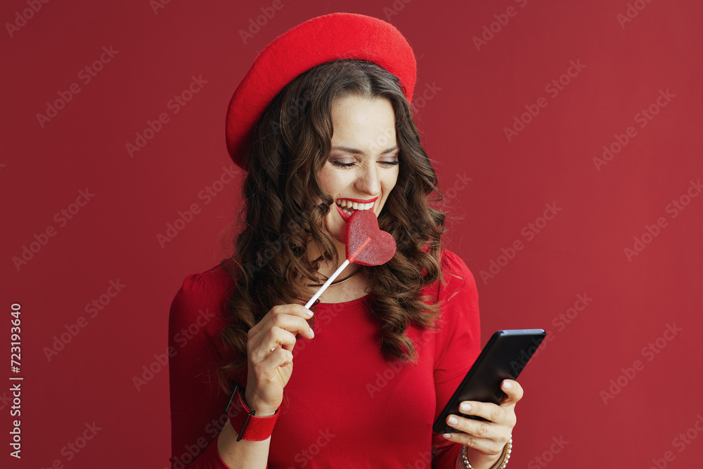 Naklejka premium woman isolated on background with heart shaped candy using phone