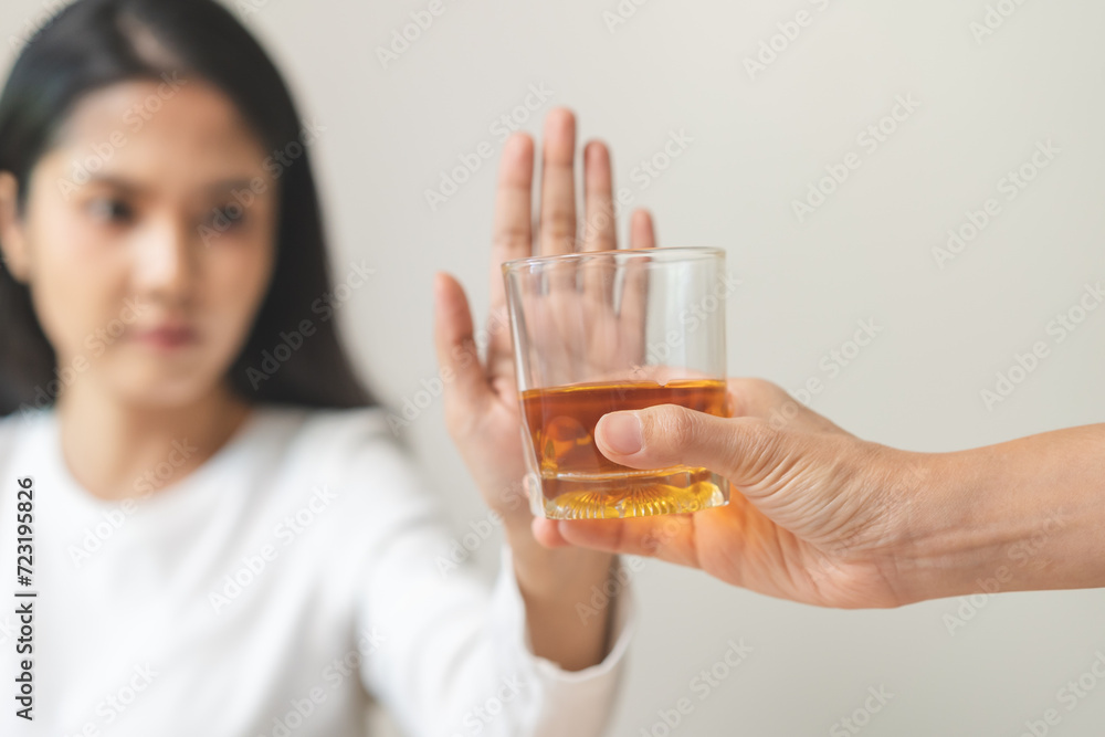 Alcoholism, depressed asian young woman hand refuse alcoholic beverage, drink whiskey while person holding glass give to her. Treatment of alcohol addiction, having suffered abuse problem alcoholism. Alcoholism, depressed asian young woman hand refuse alcoholic beverage, drink whiskey while person holding glass give to her. Treatment of alcohol addiction, having suffered abuse problem alcoholism.