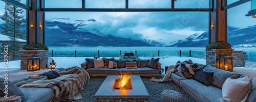 Wide angle view of a large outdoor patio with fireplace with rock pavers. beautiful blue lake and huge mountain with snow on background. photo