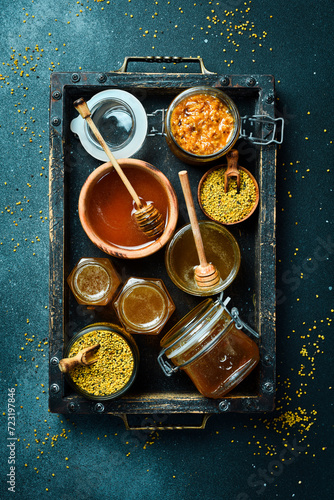 Set of honey, bee products and honeycomb honey. On a dark background. Top view. In a wooden box. © Yaruniv-Studio
