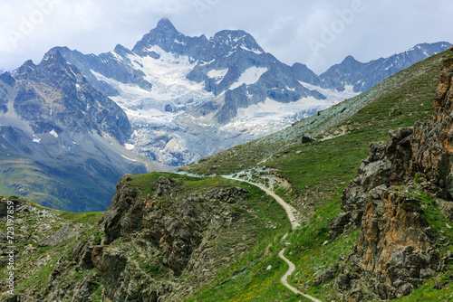 Alpine mountain view with snowy peaks covered with clouds from Rothorn and mountain trail