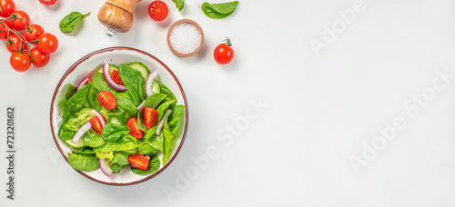vegetable salad of fresh tomato, cucumber, onion, spinach and lettuce on a white background. Healthy, clean eating. Long banner format. top view