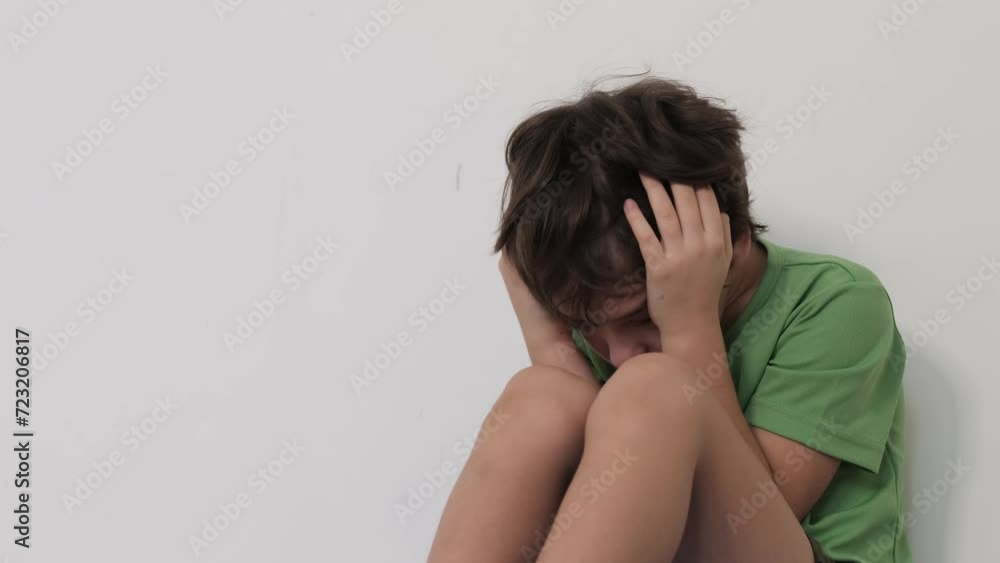 Small child in a protective pose, concealing his face from the world, indicative of deep emotional distress or social anxiety. Can illustrate child welfare articles or mental health awareness Small child in a protective pose, concealing his face from the world, indicative of deep emotional distress or social anxiety. Can illustrate child welfare articles or mental health awareness