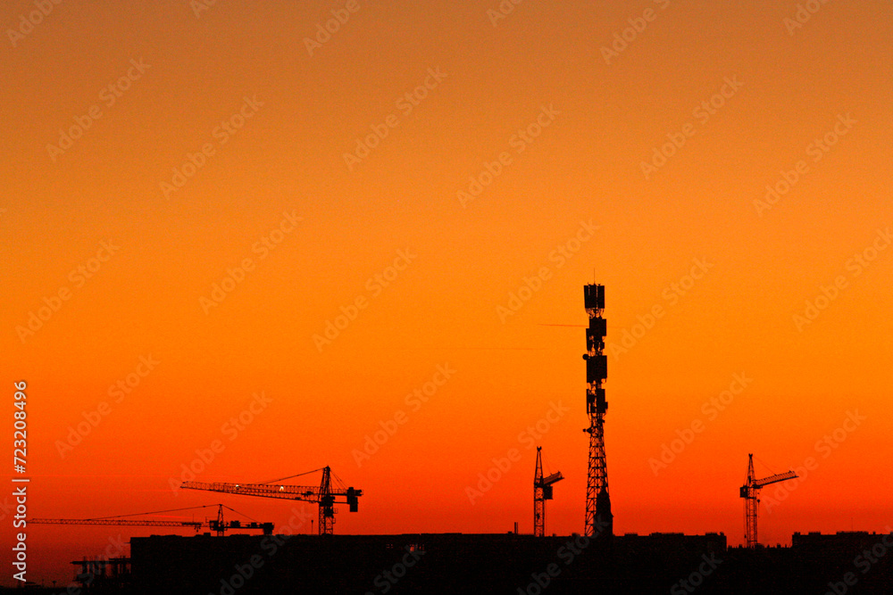 Telecommunication tower at sunset. Cell Site Digital Cellular Telecommunication Tower Network Antenna and cranes on clear sunset orange sky background