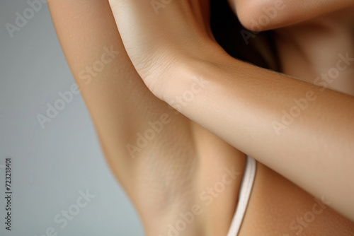 Closeup young beautiful woman showing armpit with smooth clean skin on solid background photo