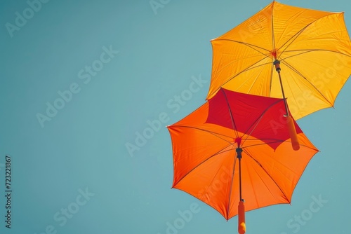 Upward view of two orange umbrellas under a clear blue sky, abstract and minimalist design concept