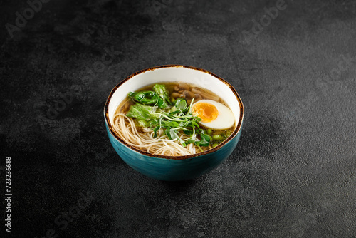 Traditional ramen with egg, greens, and mushrooms in a blue bowl