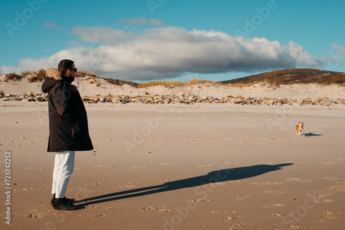 Man and dog on a serene beach in Larino, Galicia photo