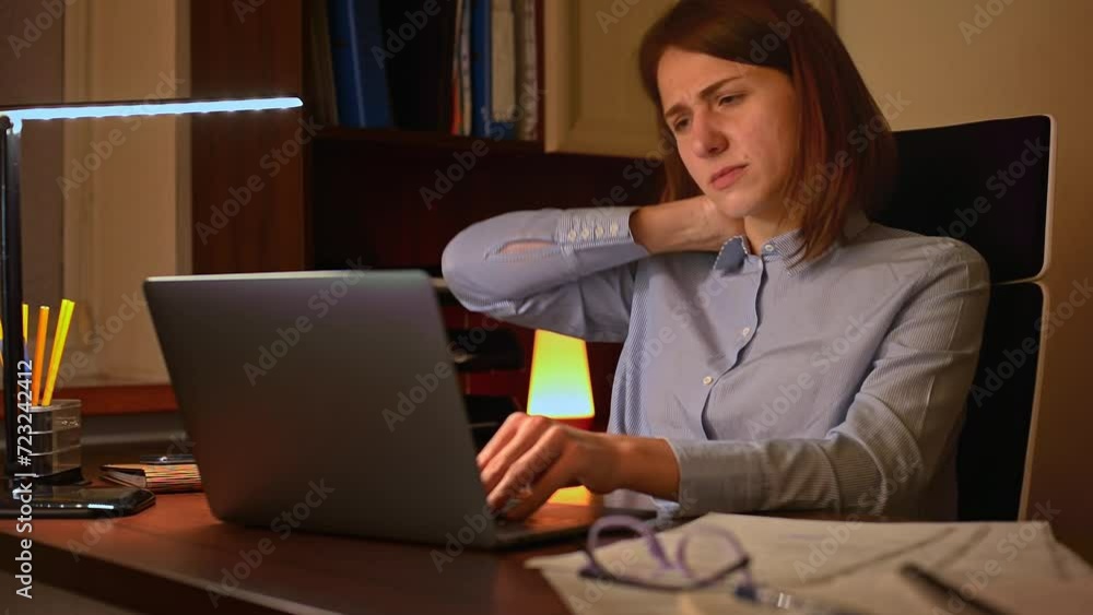 A professional woman is typing on her laptop with concentration. She starts to feel the strain on her neck and shoulders. She stops and rubs her neck, trying to ease the pain and stiffness. A professional woman is typing on her laptop with concentration. She starts to feel the strain on her neck and shoulders. She stops and rubs her neck, trying to ease the pain and stiffness.