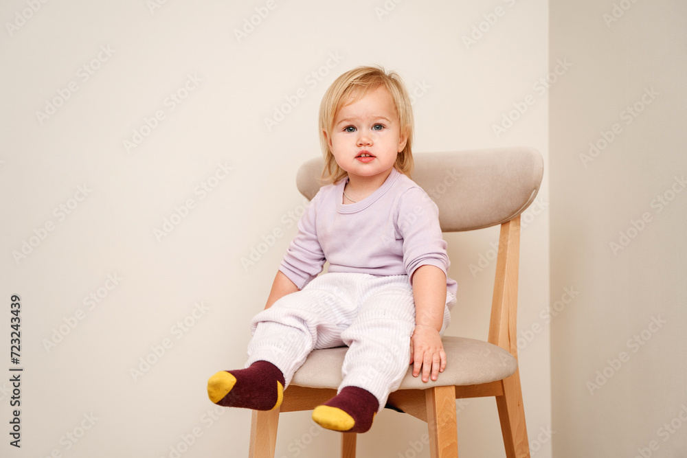 Little child toddler girl sitting on a chair, portrait of a cute Caucasian blonde child Little child toddler girl sitting on a chair, portrait of a cute Caucasian blonde child