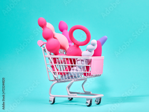 Female pink sex toys in shopping trolley over turquoise background