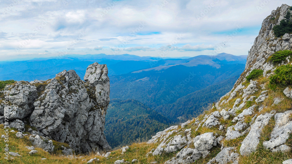 Buila Mountains in autumn. On a high altitude plateau, numerous cliffs are rising to the sky. The eroded calcareous rocks are sharp. From the ridge beech forests can be seen. Carpathia, Romania.
