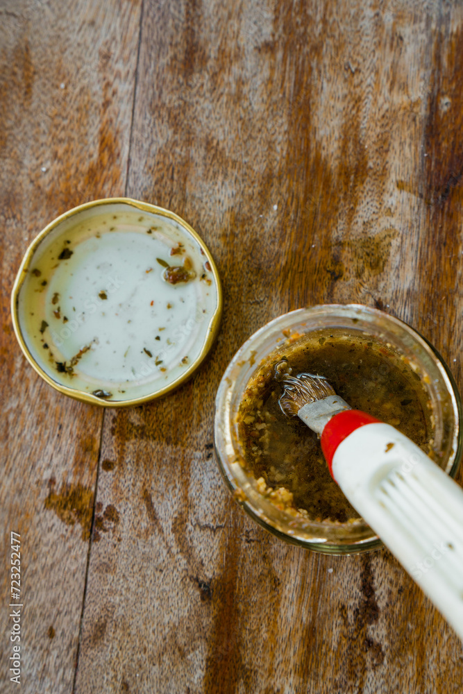 Close up of jar of chimichurri sauce with a food brush, to spice the pork meat, in glass jar. Argentinian food Close up of jar of chimichurri sauce with a food brush, to spice the pork meat, in glass jar. Argentinian food