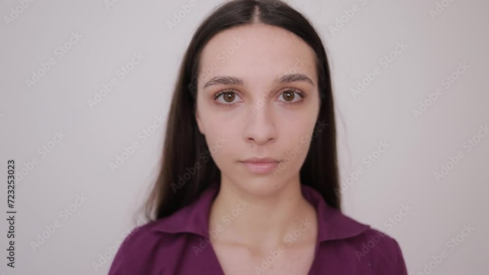 Portrait of a smiling young woman with big eyes. Brunette on a gray background. Portrait of a smiling young woman with big eyes. Brunette on a gray background.