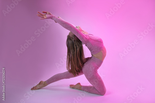 A dancer demonstrates dance warm-up movements in the style of modern dance on a pink background.