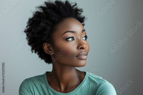 Thoughtful African American woman with makeup and natural curly hair looking away  studio background
