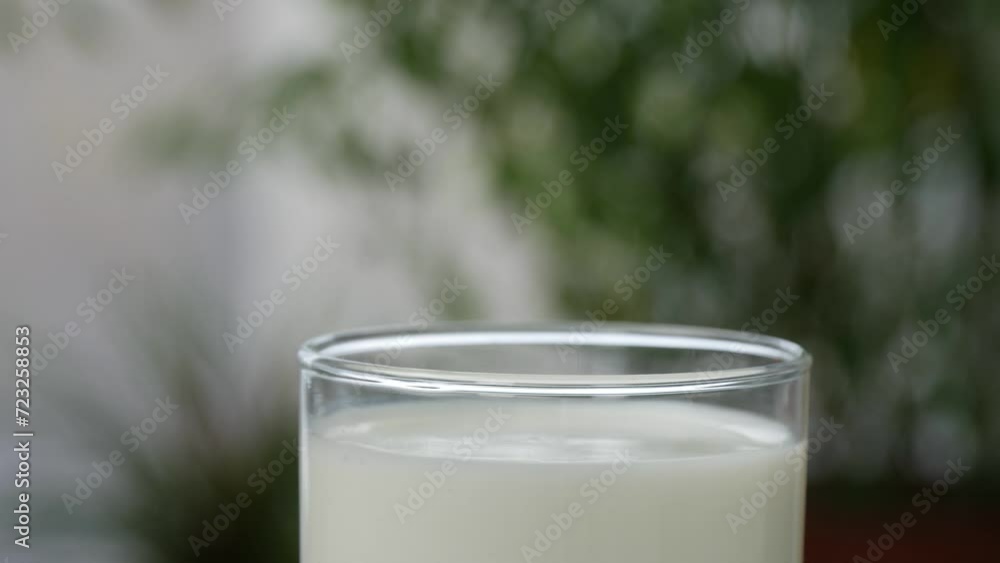 Blurred Shooting with a Hand Putting a Glass with Hot and Fresh Milk on the Table. Bio Dairy Products Concept. Blurred Shooting with a Hand Putting a Glass with Hot and Fresh Milk on the Table. Bio Dairy Products Concept.
