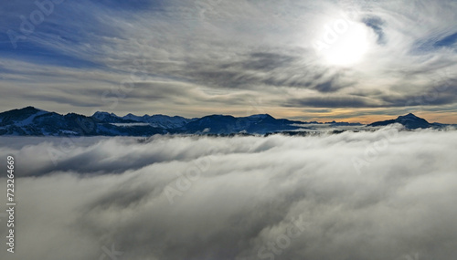 Drohnenaufnahme im Winter mit Nebel im Tal und Sonne im Gebirge photo