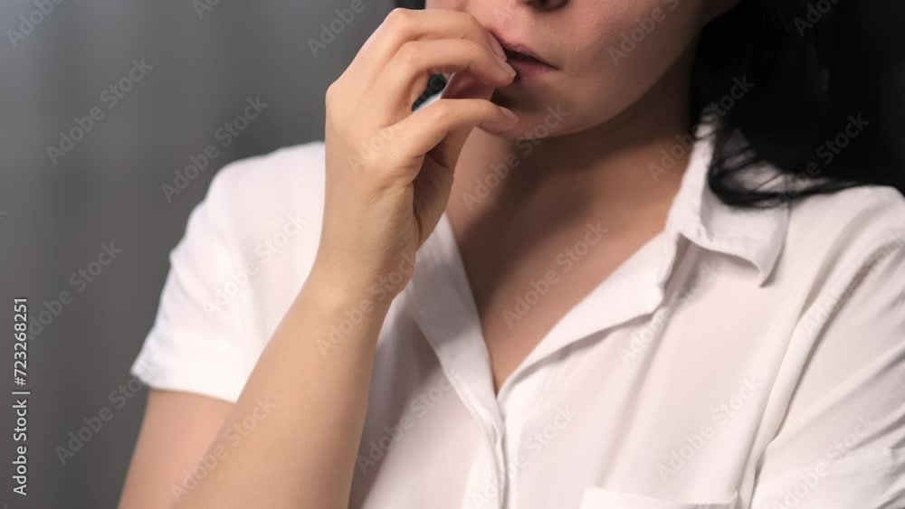 Individual exhibiting signs of nervousness with the act of biting her nails. Pertinent for discussions on anxiety disorders and stress relief techniques. Individual exhibiting signs of nervousness with the act of biting her nails. Pertinent for discussions on anxiety disorders and stress relief techniques.