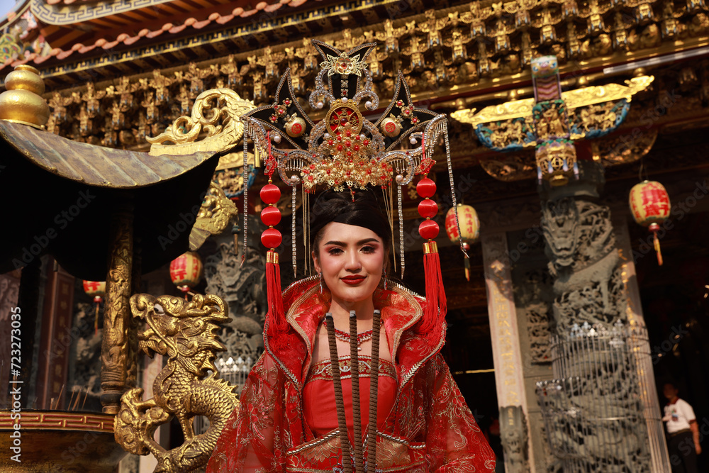 Portrait Asia woman with a red cheongsam qipao dress  with the golden dragon statue at shrine, Chinese New Year