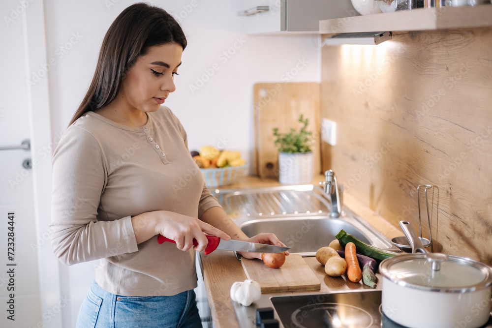 A young beautiful woman is preparing lunch in her kitchen at home. Vegan