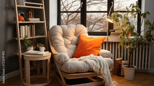 Comfortable armchair with an orange pillow creates a welcoming reading corner near the window © Ihor