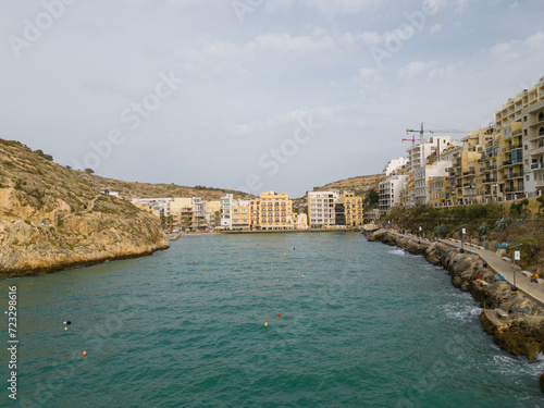 Xlendi bay with hotels waterfront aerial view from the sea Gozo island, Malta.