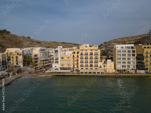 Xlendi hotels waterfront at Xlendi bay on a calm afternoon. Aerial view of traditional Saint Patrick\'s Hotel with the restaurant on Gozo island. Date: 25.10.2023 Xlendi Bay, Gozo, Malta
