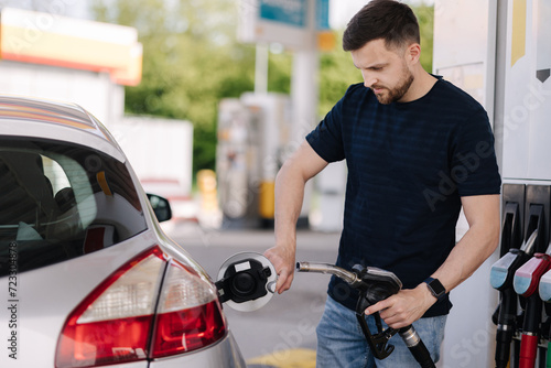 Handsome bearded man refueling car at self service gas station. Petrol concept photo