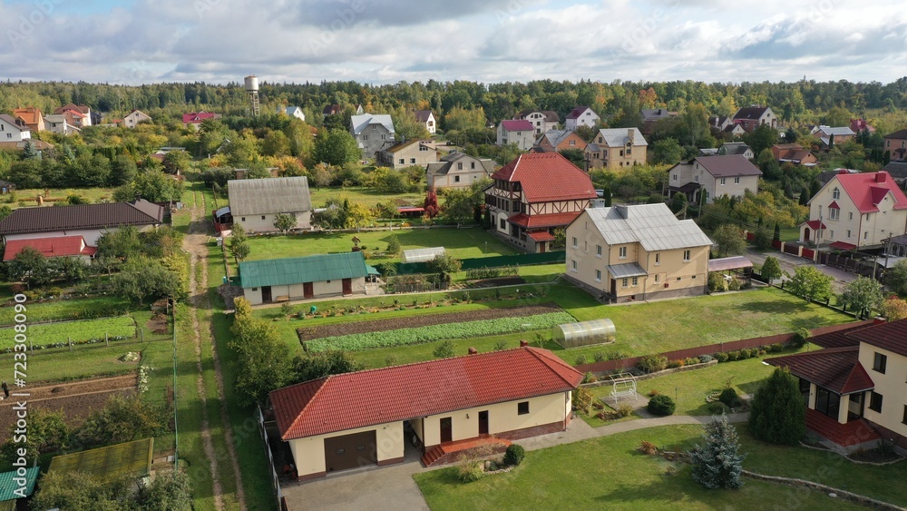 Picturesque eco-settlement, a village in the forest with fresh air. Cottage village among the forest, shooting from a height in the fall. Private houses, outbuildings, roads. Plots, private territory.