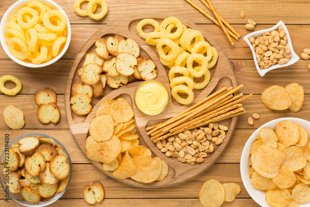 Various unhealthy snacks on wooden background, top view