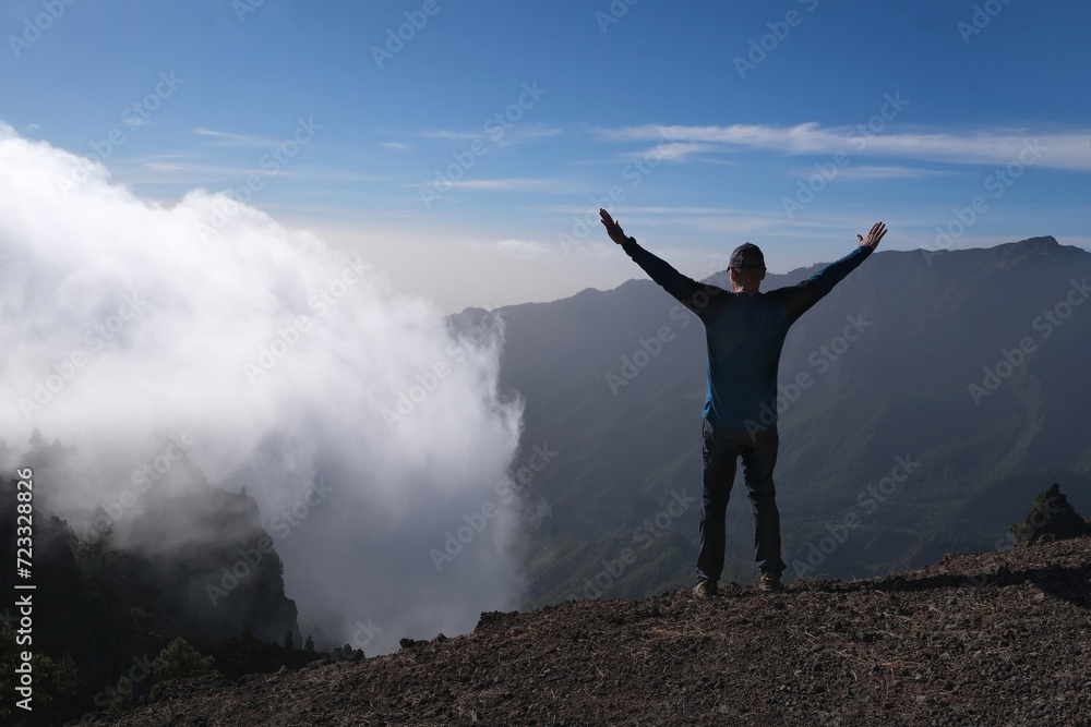 Silhouette of man with raised arms in mountains over clouds. National Park Caldera de Taburiente, La Palma, Canary Islands, Spain Silhouette of man with raised arms in mountains over clouds. National Park Caldera de Taburiente, La Palma, Canary Islands, Spain