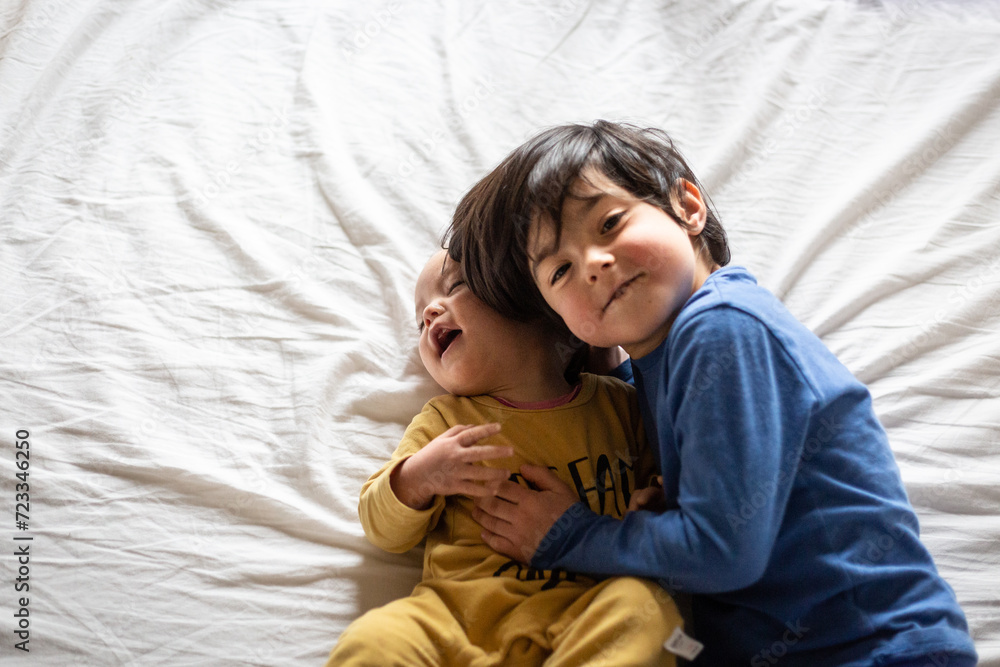 upper view on two happy children hugging each other on the parent's bed upper view on two happy children hugging each other on the parent's bed