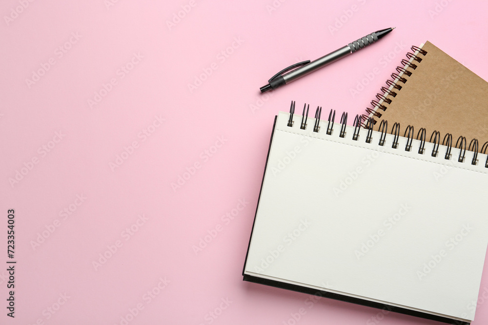 Notebooks and pen on pink background, top view. Space for text Notebooks and pen on pink background, top view. Space for text