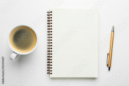 Notebook, coffee and pen on white table, flat lay. Space for text
