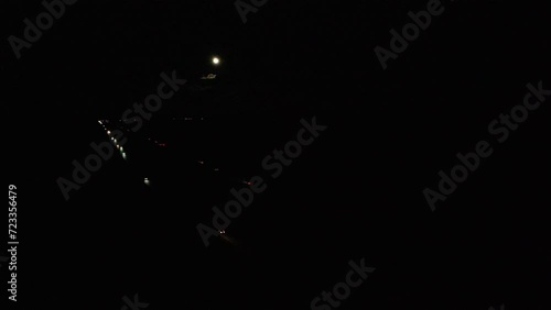 Aerial full moon over dark night desert highway traffic. Nevada desert freeway driving. Road to Las Vegas. Dark with headlights and tail lights glowing in remote rural area.