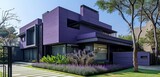 A state-of-the-art house in a deep, royal purple, complemented by a minimalist backyard. The wrought iron gate displays sleek and stylish modernity. Captured in the clear, bright light of a sunny day