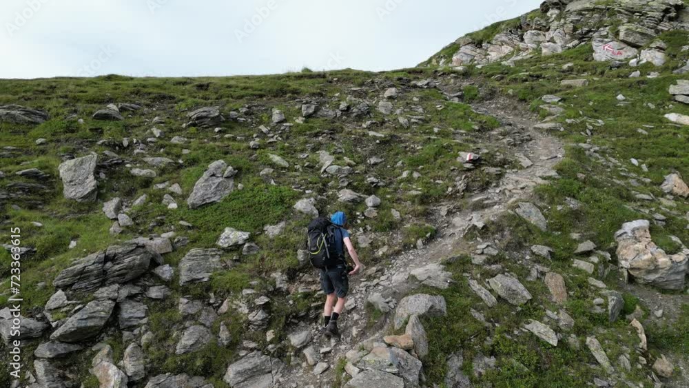 Male hiker (man) with trekking backpack hiking on path towards mountain panorama in Texel group, South Tyrol, Italy Male hiker (man) with trekking backpack hiking on path towards mountain panorama in Texel group, South Tyrol, Italy
