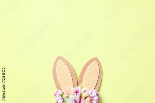 Easter bunny ears decorated flowers on pastel green background. Flat lay, top view.