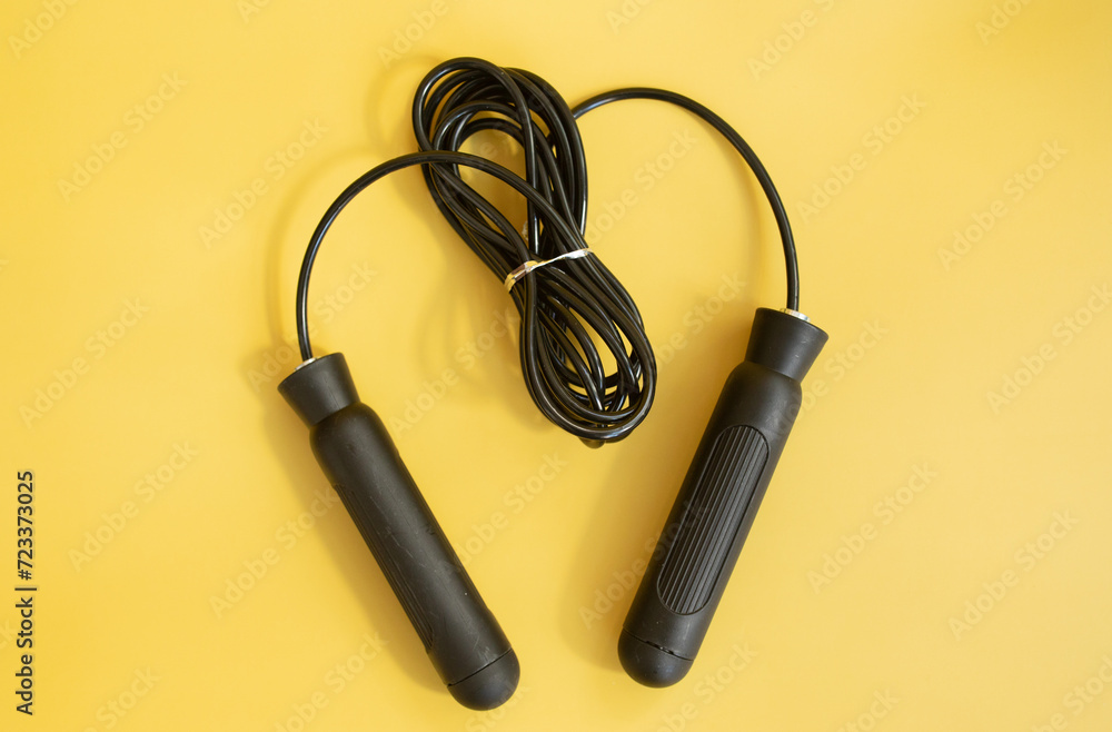 Skipping rope with black handles on the yellow background. Skipping rope with black handles on the yellow background.