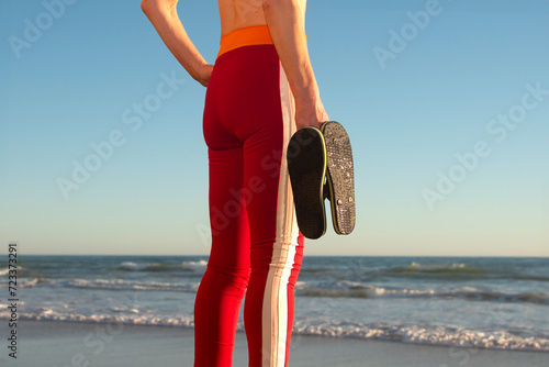 woman holding a pair of flip flop sandals at the beach photo