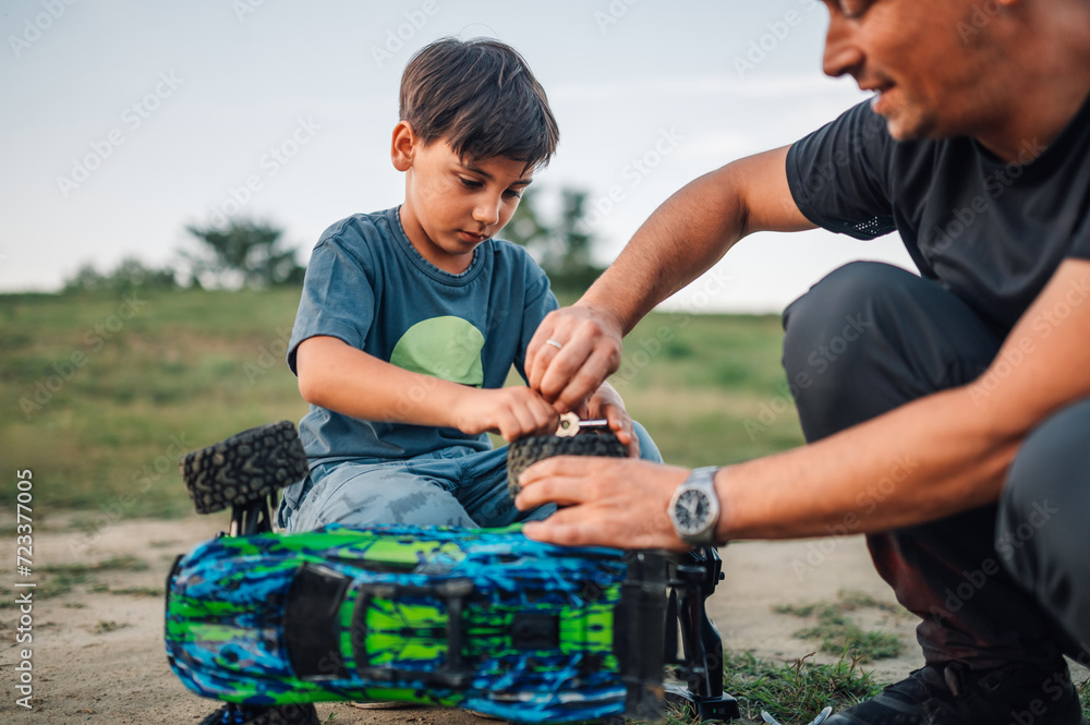 Boy repairing a tire on a broken toy car while his father is assisting him. Boy repairing a tire on a broken toy car while his father is assisting him.