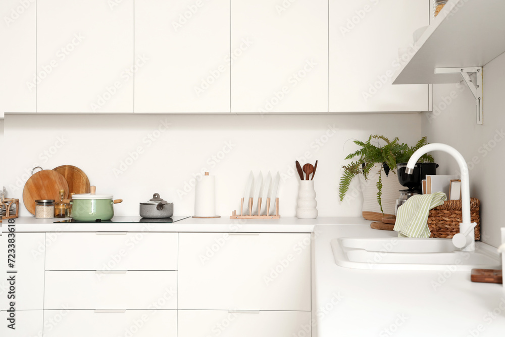 White counters with electric stove, sink and utensils in modern kitchen